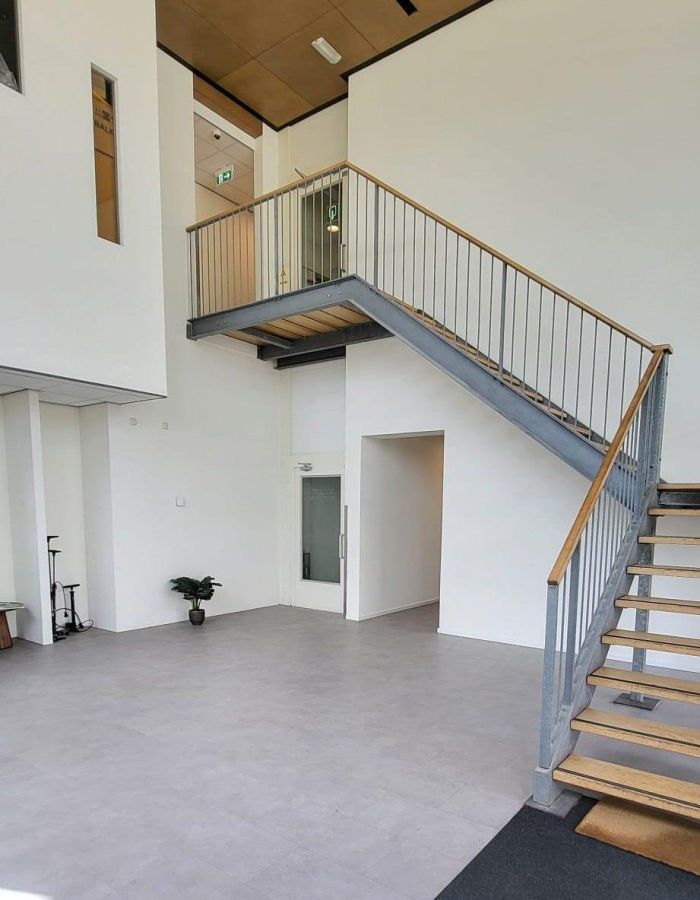 Transformatie voormalig hotel Born – lichte entreehal met stalen trap, vide, veel daglicht en strakke afwerking