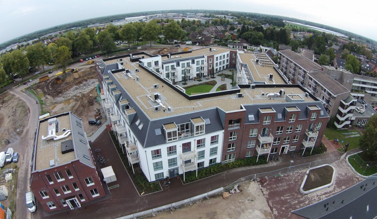Hof te Berkel Horst – luchtfoto van U-vormig appartementencomplex met binnentuin, mansardedaken en witte/rode baksteen; bouwterrein op voorgrond