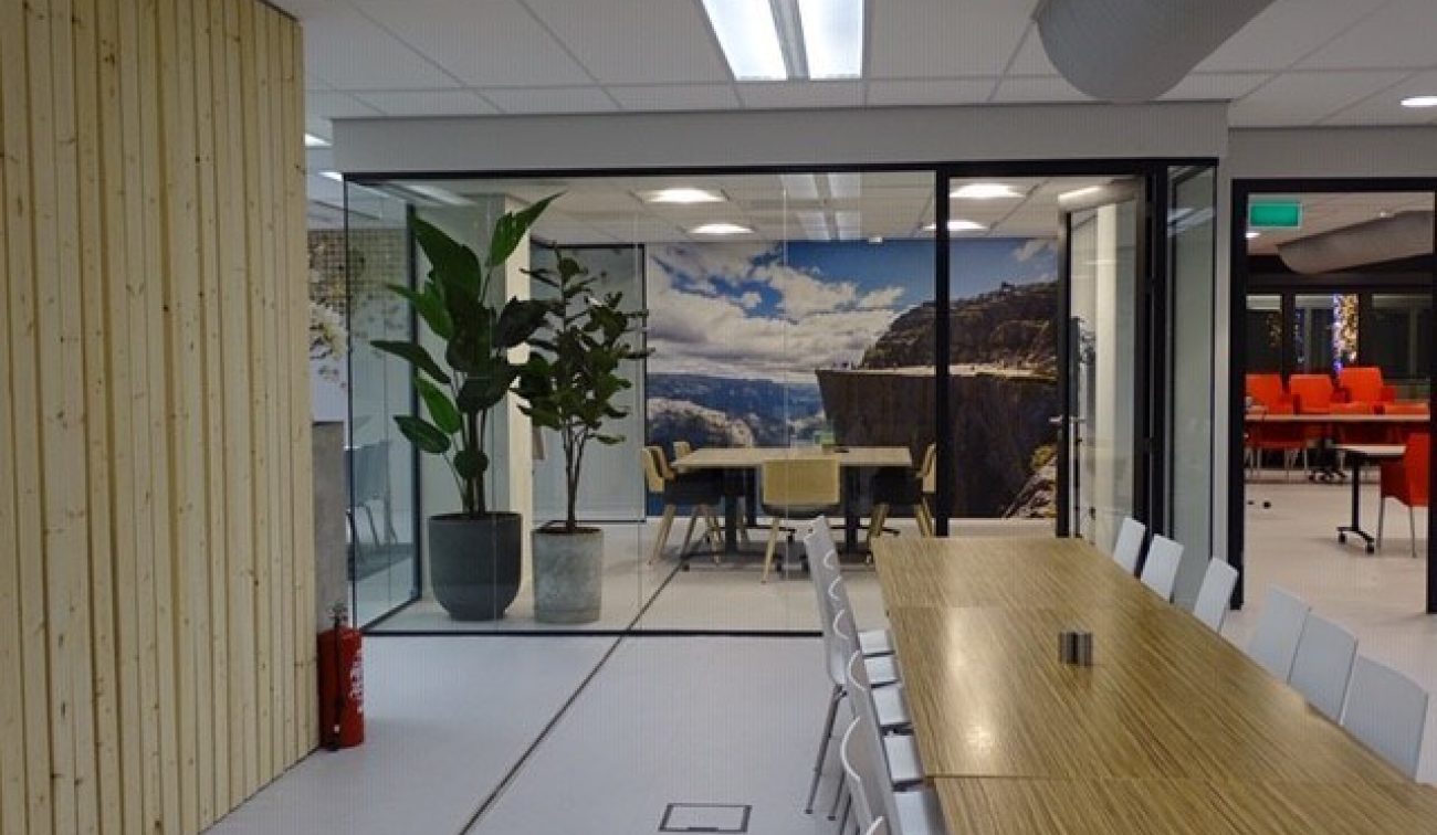 Renovatie Meeting Plaza: open ruimte met lange tafel, glazen box, natuurprint en witte stoelen