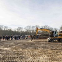Start bouw Bosrijk Mariëndaal in velp : graafmachine aan het werk terwijl omwonenden en kopers toekijken langs de bouwplaats.