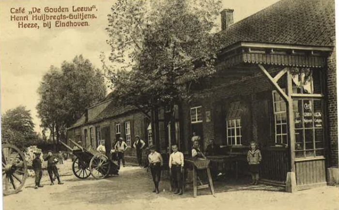 Historische dorpsstraat met kinderen, kar en oude bakstenen gebouwen voor een café in landelijke omgeving