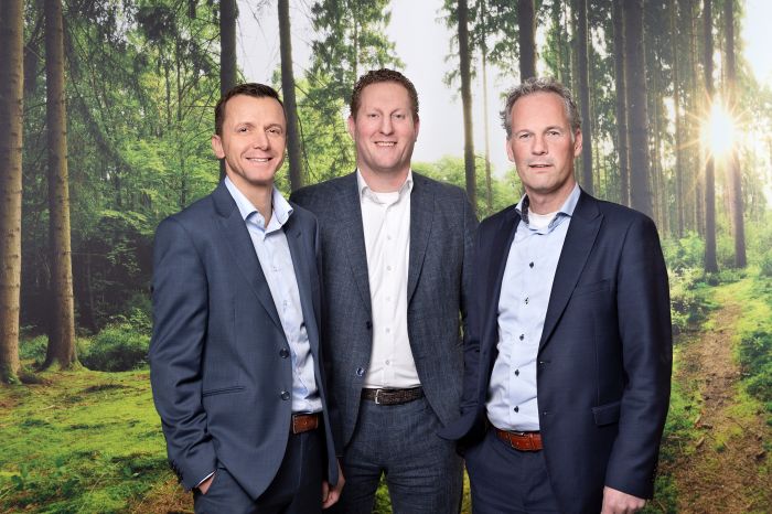 Drie zakenmannen in pak poseren voor bosrijke achtergrond met zonlicht, moderne zakelijke portretfoto