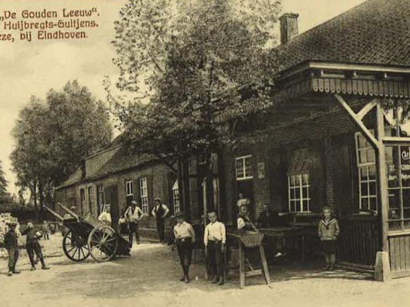 Historische dorpsstraat met kinderen, kar en oude bakstenen gebouwen voor een café in landelijke omgeving