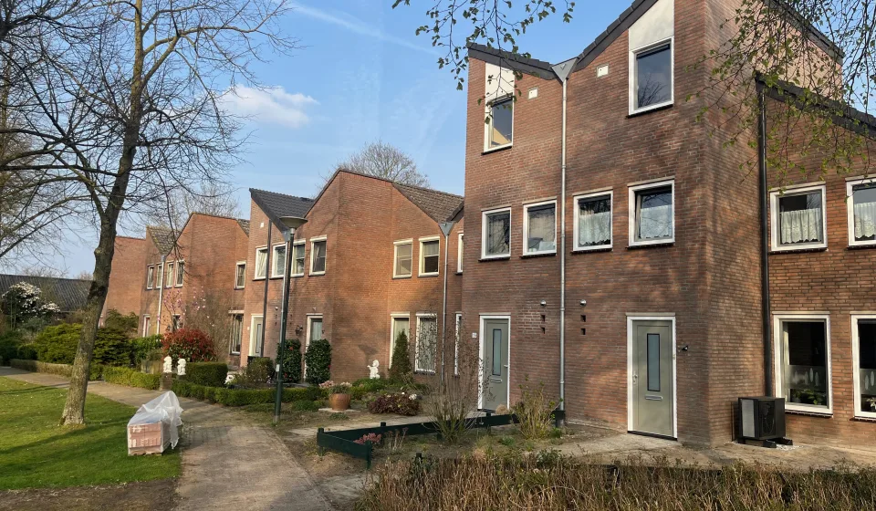 Rijwoningen met bakstenen gevels, voortuinen en wandelpad langs groenstrook