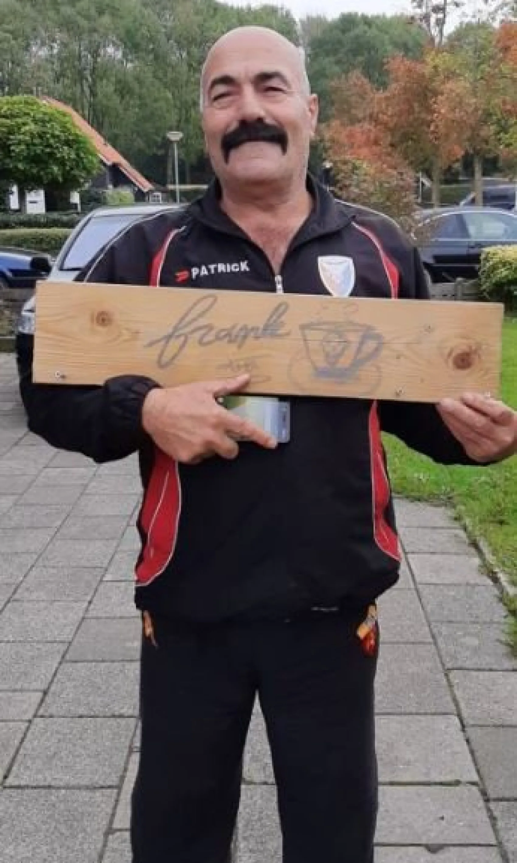 Man houdt houten bord met handgeschreven tekst vast in woonwijk