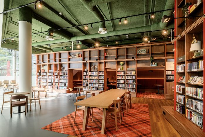 Bibliotheekinterieur met groen plafond, hoge houten kasten, studie-nissen en lange leestafel.