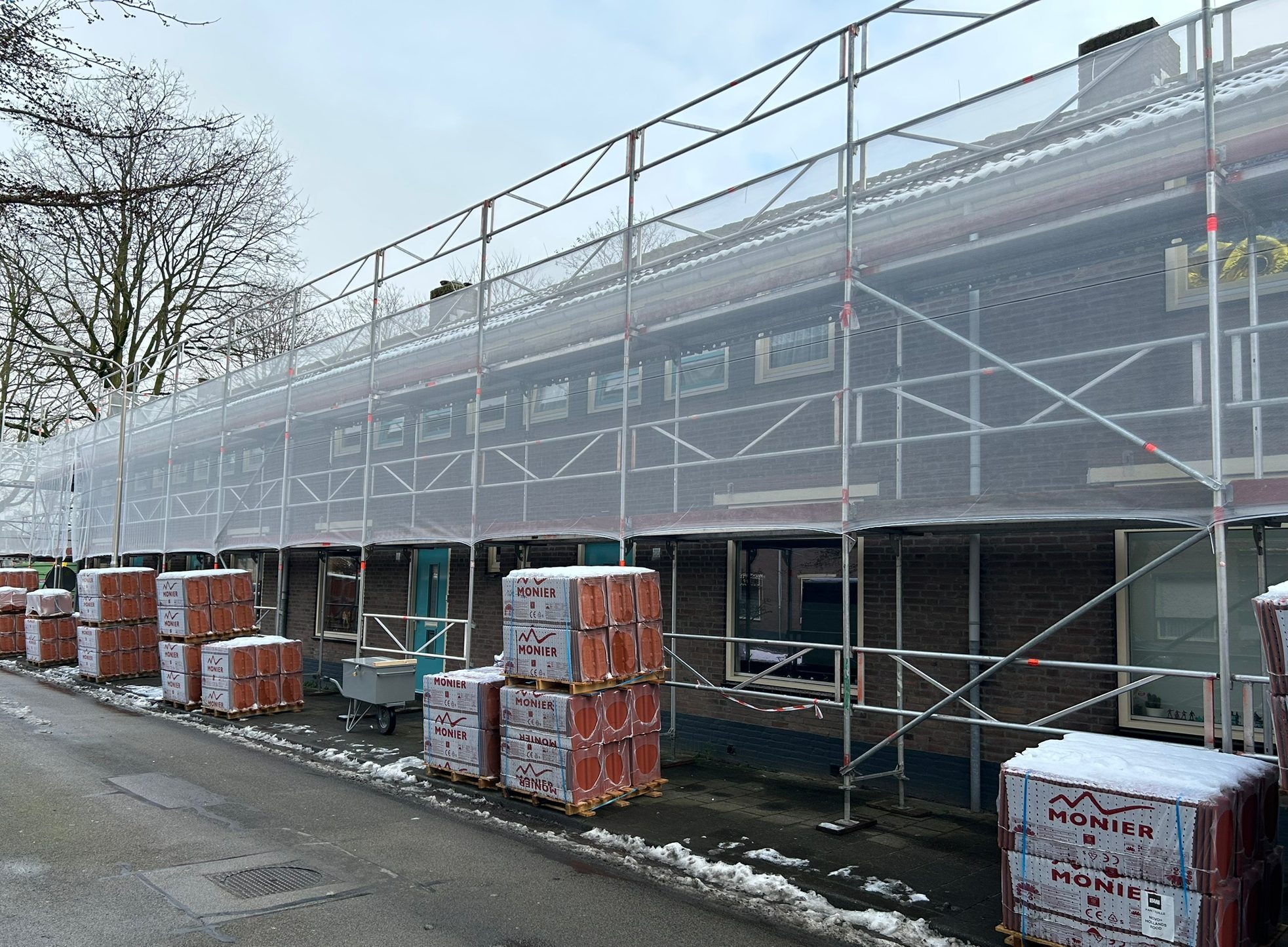 Berkdijk Tilburg groot onderhoud: steigers met doek dakpannen op pallet, winterse straat met sneeuw