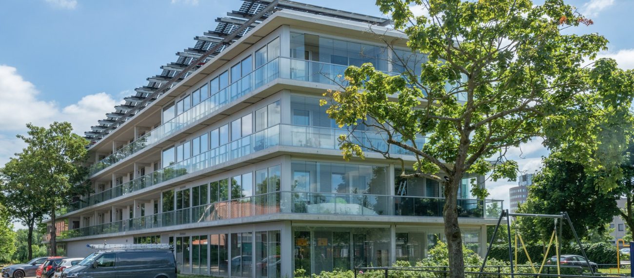 Ander zijaanzicht van het nieuwbouwproject in de Gestelse Buurt in ’s-Hertogenbosch, met zicht op de gevels en buitenruimte van het appartementencomplex.