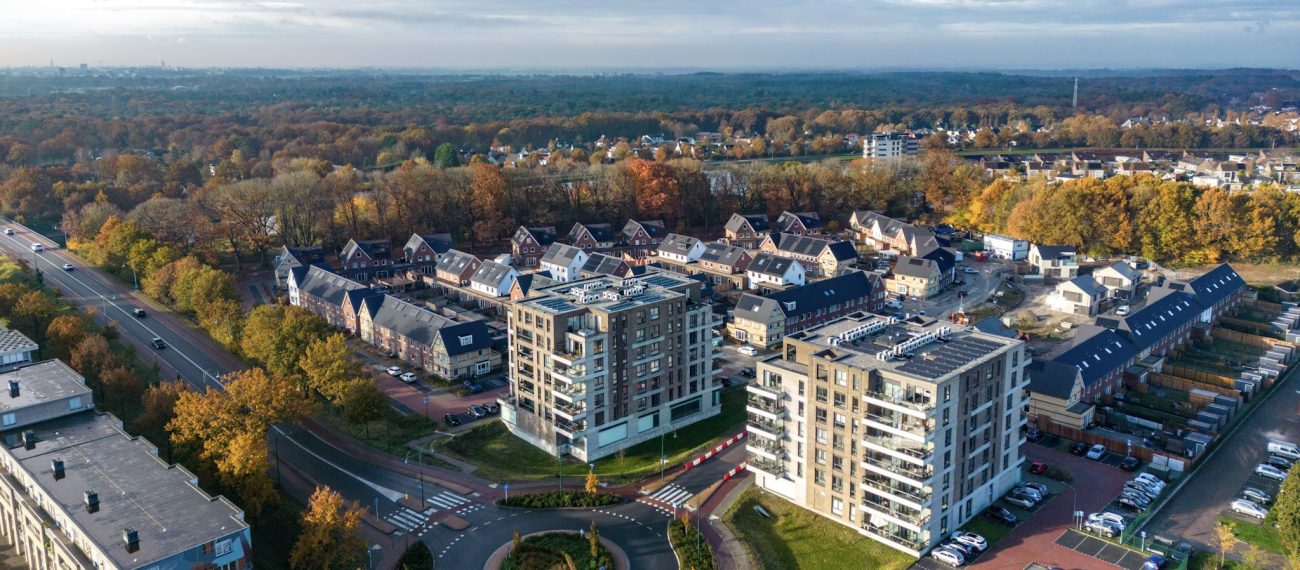 Luchtfoto van het voltooide nieuwbouwproject Wilhelminahaven in Oosterhout, met twee moderne appartemententorens, rijwoningen en groene woonomgeving.