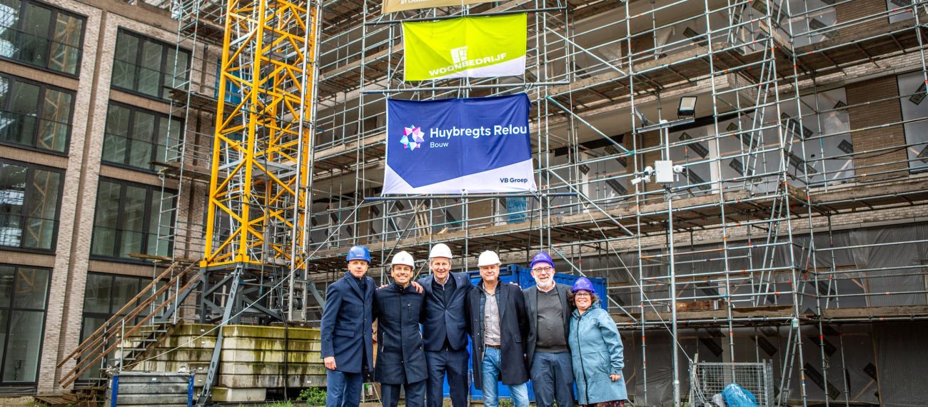 Groep werknemers van Huybregts Relou die geposeerd staan voor een bouwproject