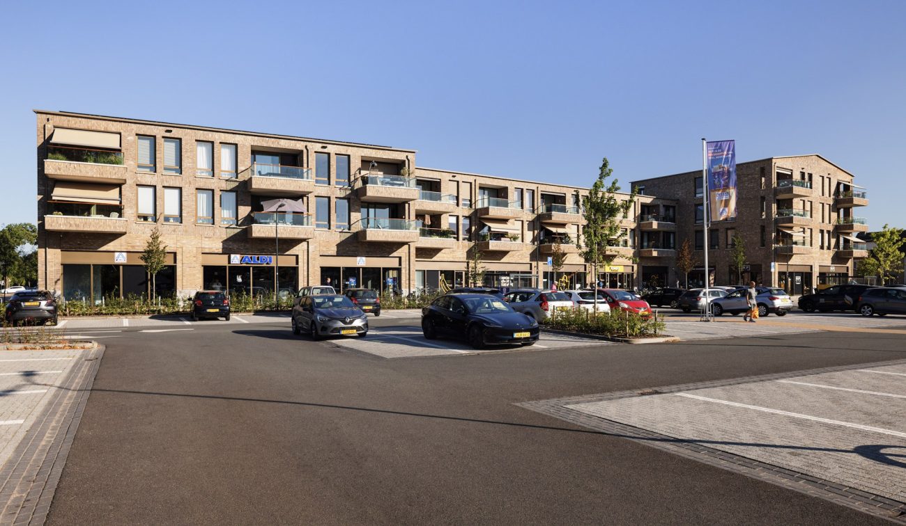 Nieuwbouw De Scheperij Teteringen: appartementen met balkons boven winkels, baksteen en parkeerplein