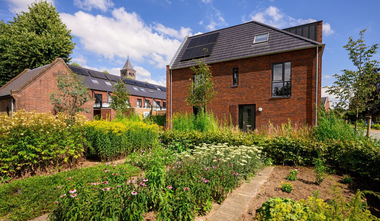 Nieuwbouwwoning in Kloostervelden in Sterksel met zonnepanelen en een kleurrijke tuin met bloemen en groen rondom.