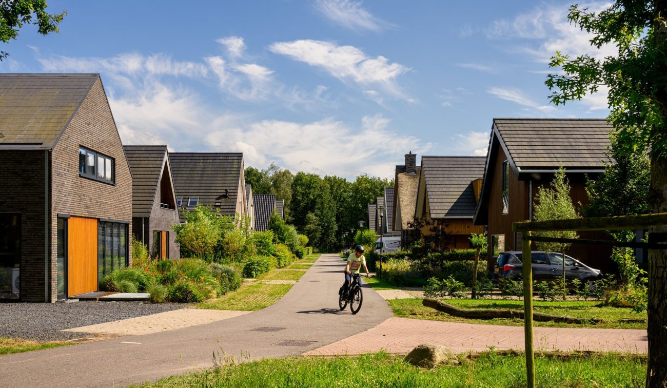 Nieuwbouwwoningen in Kloostervelden in Sterksel, met groene straten, moderne architectuur en een fietser op de weg.