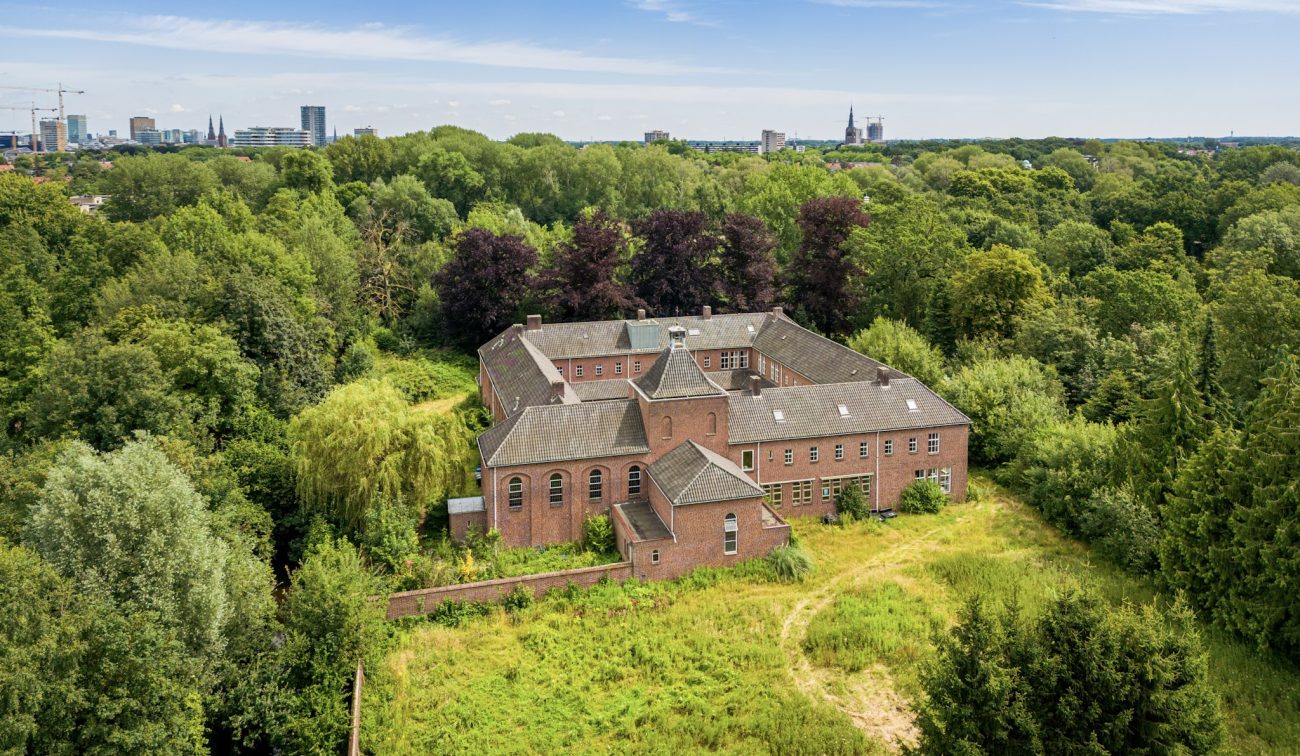 Landgoed met bakstenen gebouw midden in bosrijk landschap vanuit vogelperspectief