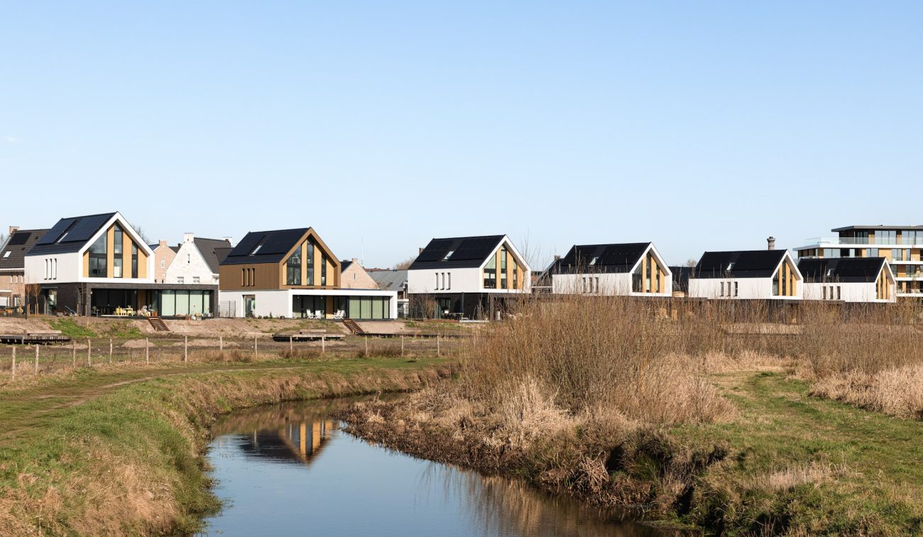 Nieuwbouwwoningen langs watergang met rietoevers in groene woonomgeving