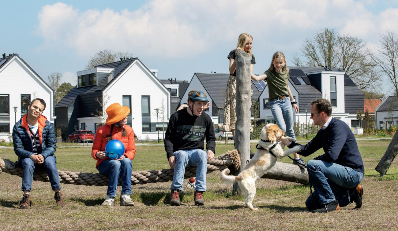 Bewoners genieten van de buitenruimte in de nieuwbouwwijk Kloostervelden in Sterksel, met moderne woningen en groene omgeving op de achtergrond.