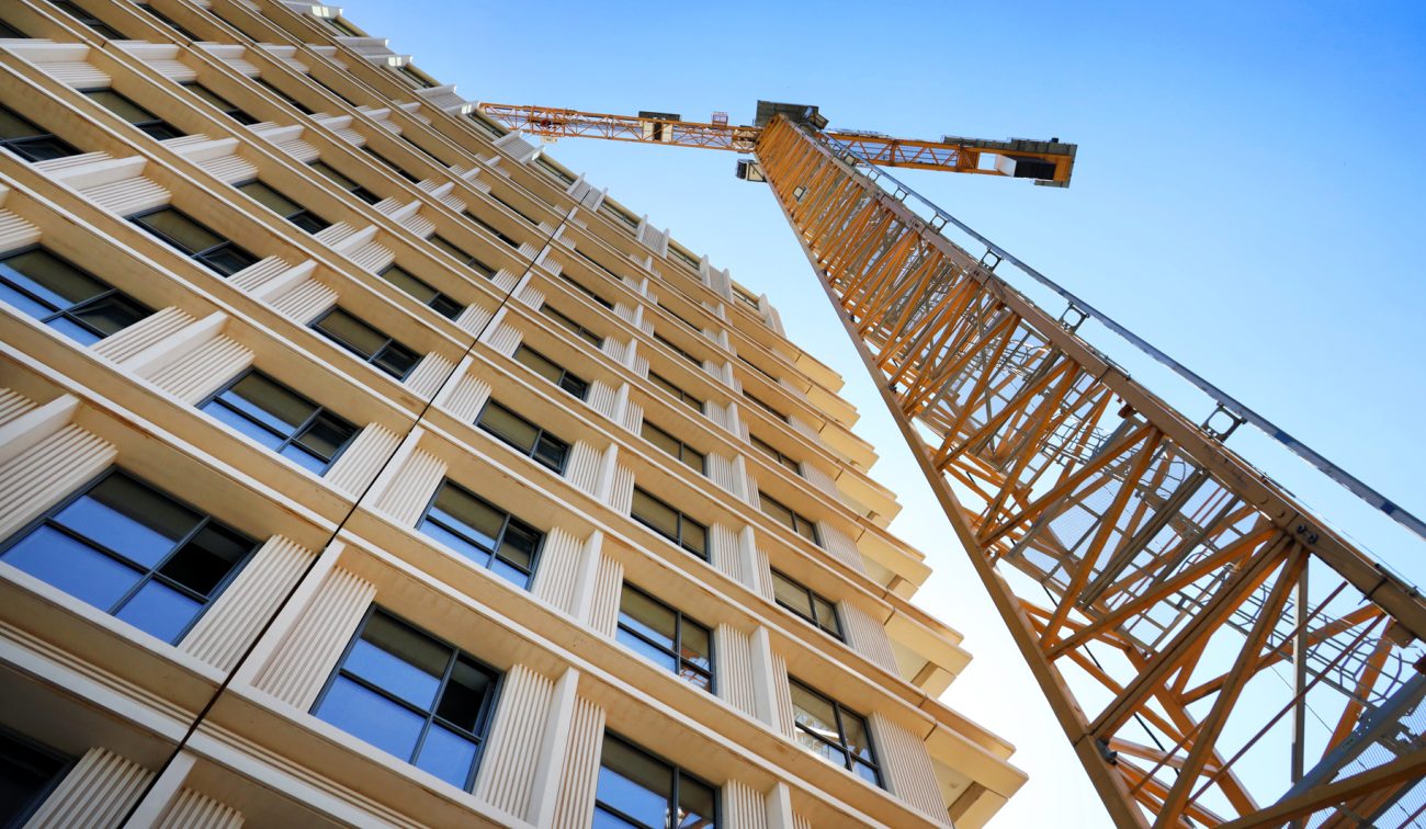 Detail gevel De Bankier met verticale lamellen en ramen, bouwkraan steekt erboven uit — Nieuwbouw De Bankier Tilburg