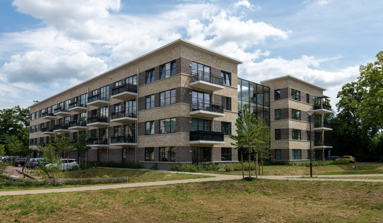 Achterzijde van het nieuwbouwappartementencomplex in de Grote Zeeheldenbuurt in Vught, omgeven door groen en een verzorgde buitenruimte.