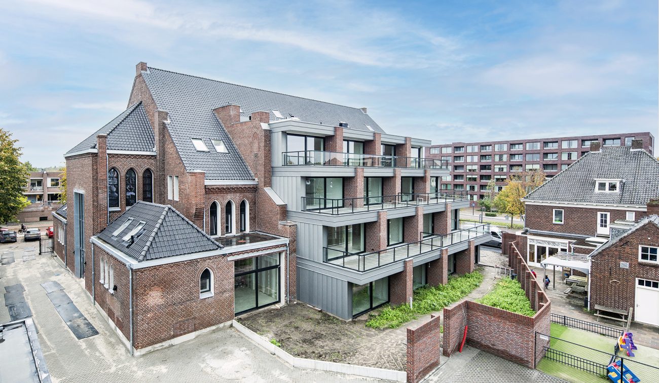 Dronefoto van De Antonius in Valkenswaard waarop de balkons en de vernieuwde gevel zichtbaar zijn na de transformatie van het gebouw.