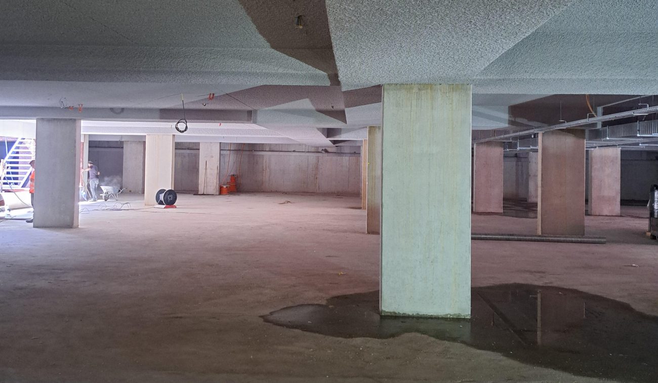 Uitbreiding en renovatie Van der Valk Hotel Wassenaar – interieur van de nieuwe parkeergarage in aanbouw met betonnen kolommen, brandwerend gespoten plafond en zichtbare installaties.