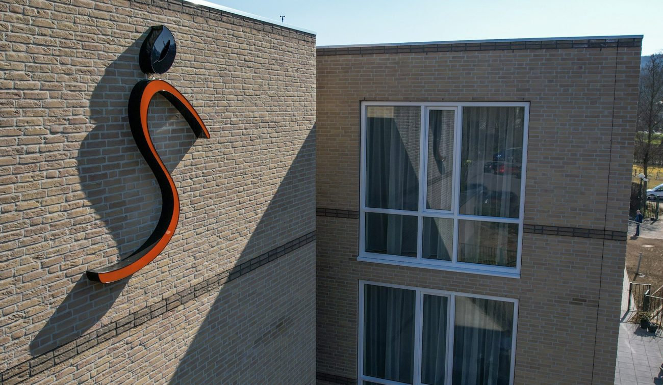 Geveldetail zorgcomplex Valkenheim Valkenburg met oranje S-logo en hoge ramen