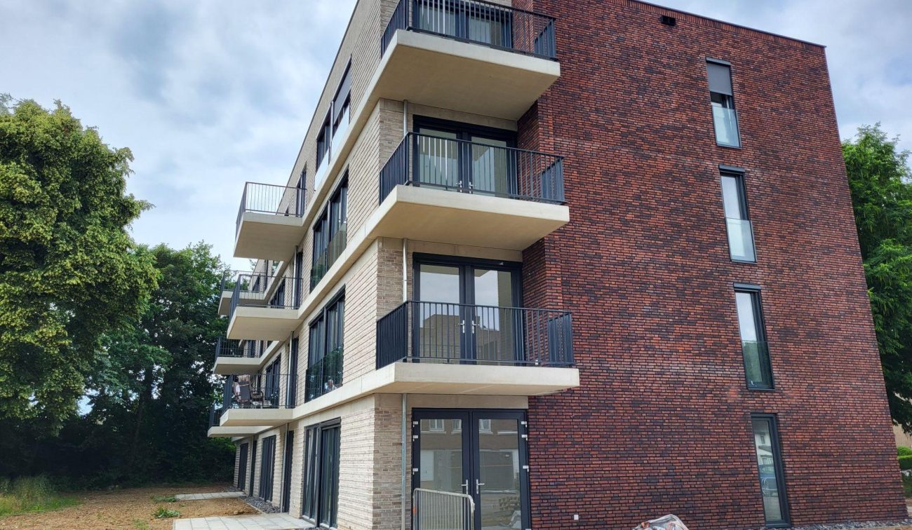 Hoekaanzicht nieuwbouw sociale huurappartementen in Margraten met balkons en roodbruine baksteen