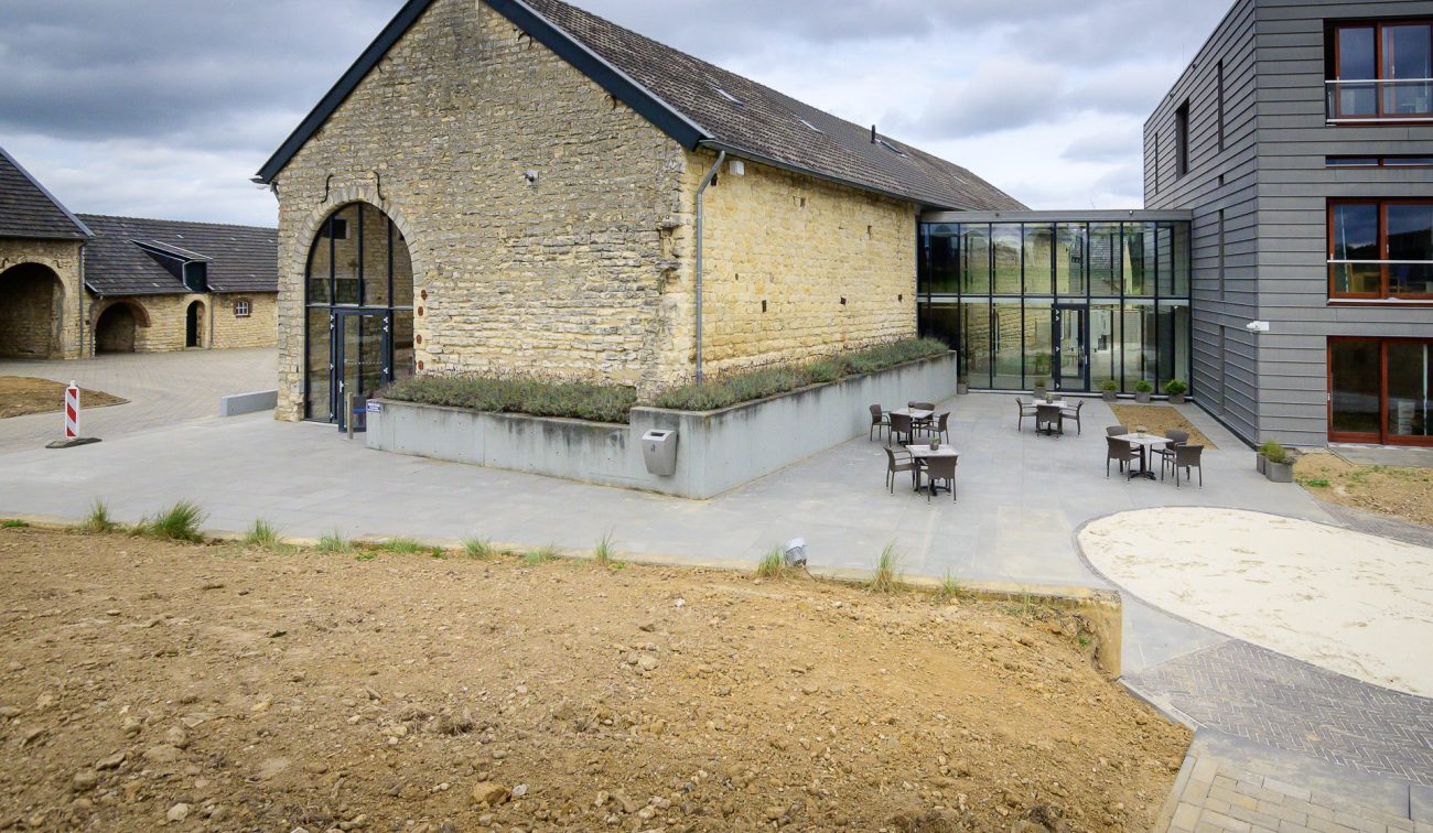 Monumentale schuur Hoeve Overhuizen met mergelstenen gevel en glazen corridor naar nieuwbouw.