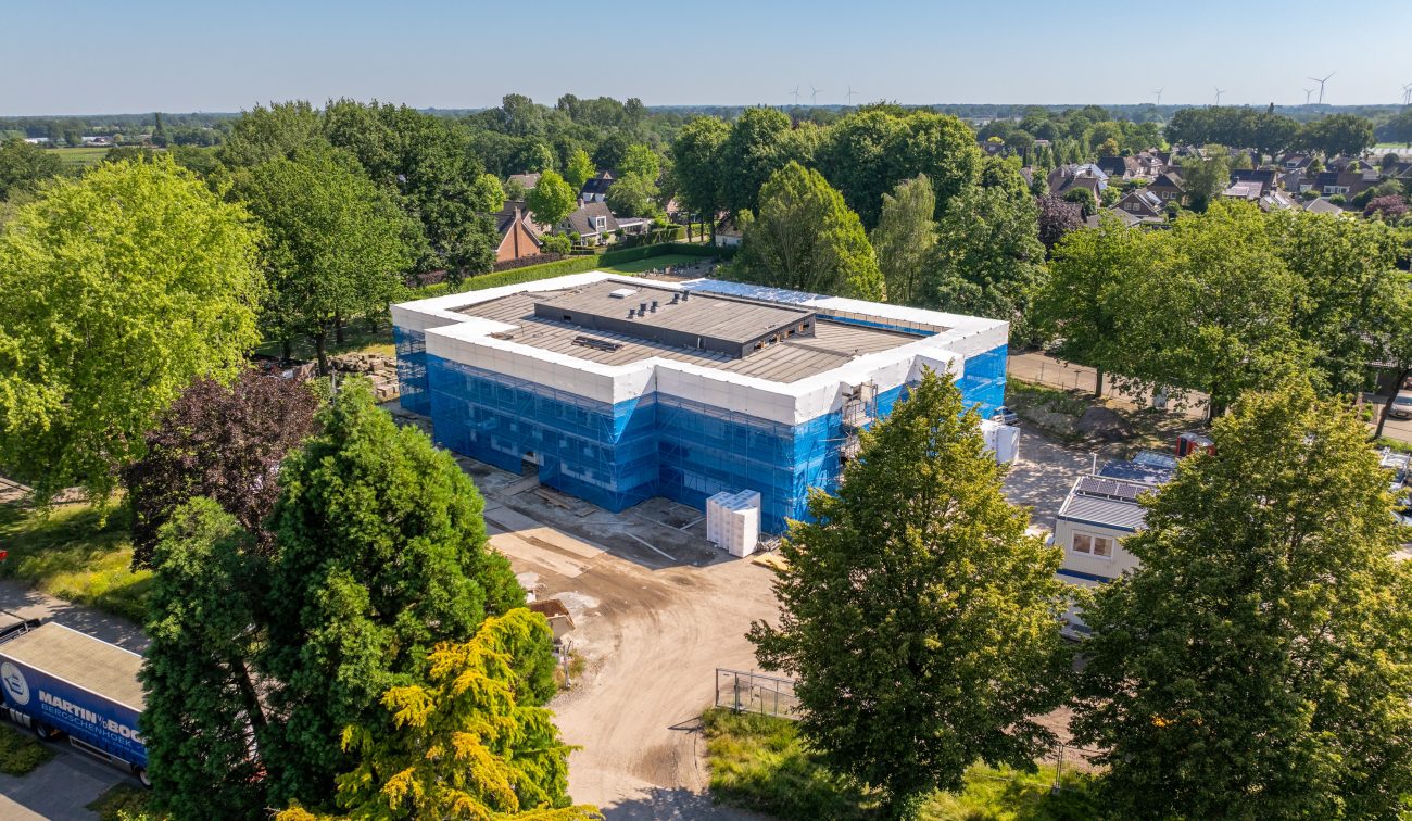 Nieuwbouw Antoniusschool Zundert: school in aanbouw met steigers blauw net en isolatie luchtfoto