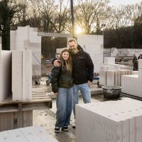 Vader en dochter knuffel elkaar op bouwplaats tijdens start bouw Bosrijk Mariëndaal in Velp tussen stapels kalkzandsteenblokken