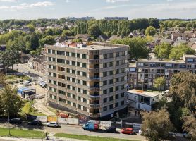 Appartementengebouw met balkons en omliggende woonwijk vanuit vogelperspectief