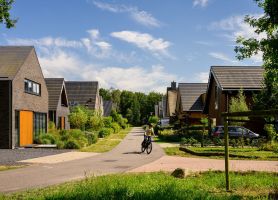 Nieuwbouwwoningen in Kloostervelden in Sterksel, met groene straten, moderne architectuur en een fietser op de weg.