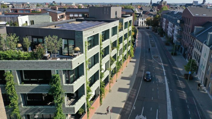 CPO Sphinx Maastricht – groene baksteengevel met verticale klimplanten en loggia’s, dakterras met zonnepanelen langs stadsstraat