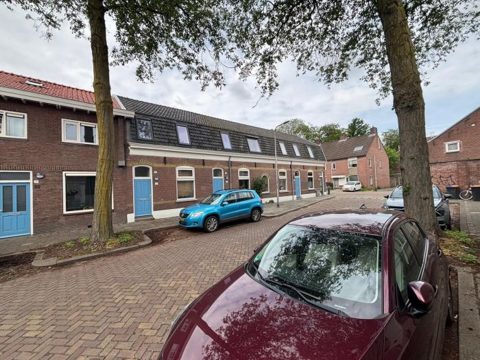 Verduurzaming van rijwoningen met vernieuwde dakkapellen en dakisolatie langs woonstraat tussen bomen