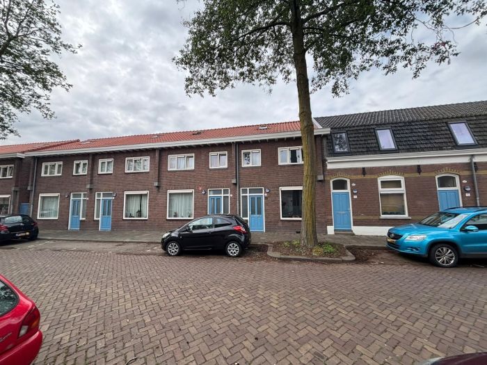 Verduurzaming van rijwoningen met vernieuwde dakramen langs woonstraat met geparkeerde auto's