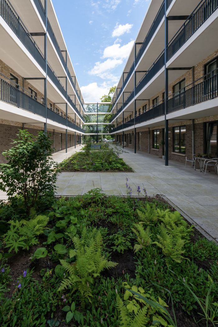 Foto van de binnentuin van het nieuwbouwcomplex in de Grote Zeeheldenbuurt in Vught met beplanting en zitplekken.