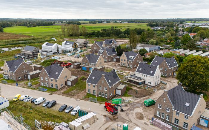 Luchtfoto van de bouw van het nieuwbouwproject Land van Anna in Goirle, met duidelijk zicht op de twee-onder-een-kapwoningen in ontwikkeling en de omliggende wijk.