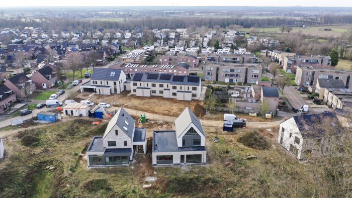 Nieuwbouw Elsloo – panorama bouwlocatie met twee vrijstaande huizen, rij nieuwbouwwoningen en bouwverkeer
