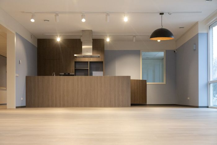 Interieur zorgcomplex Valkenburg: moderne keukenwand met kookeiland en grote hanglamp.
